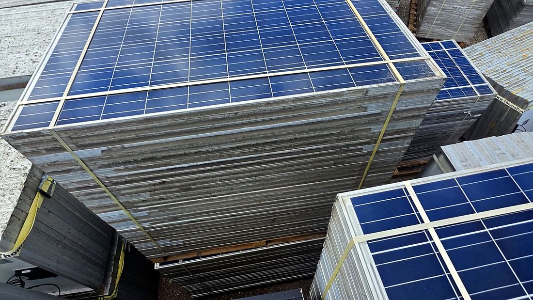 Gestapelte gebrauchte Solarmodule auf Paletten, von oben fotografiert