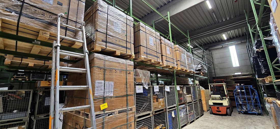 Lagerhalle mit Paletten voller Solarmodule im Hochregal und einem Gabelstapler